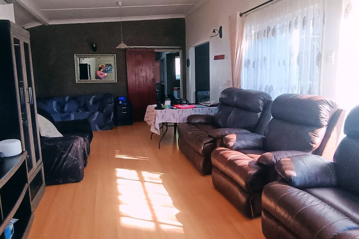 A spacious living room featuring laminate flooring and natural light, providing a comfortable area for relaxation and family gatherings.