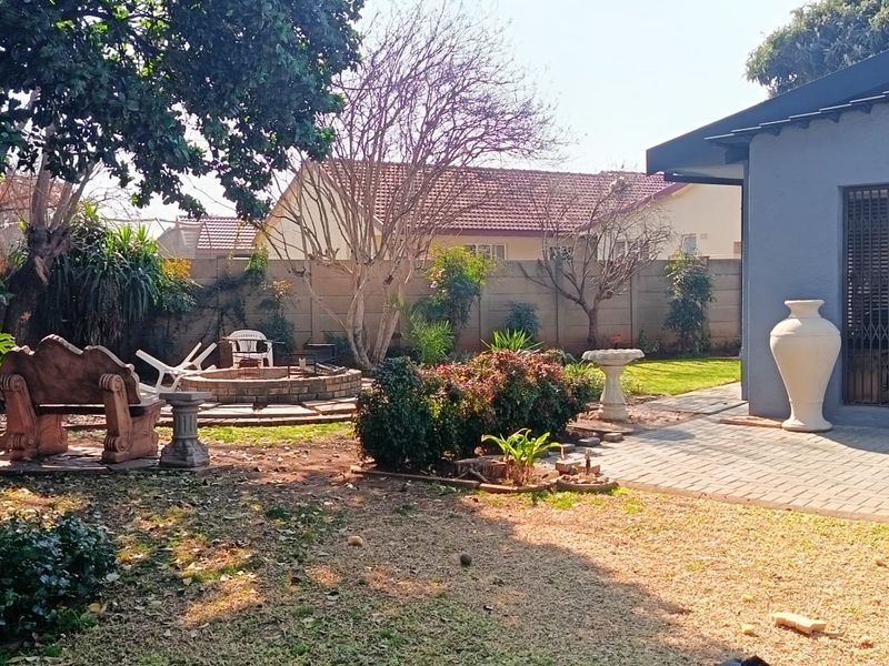 A private rear garden featuring a paved patio area, a built-in brick fire pit, and established perimeter walling.