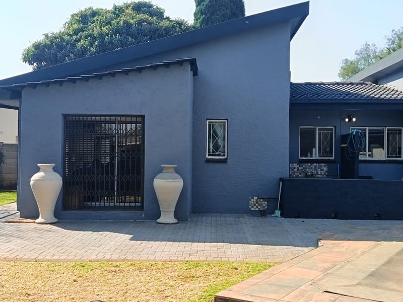 Rear view of the house featuring a paved patio area, security gates, and access to the swimming pool.