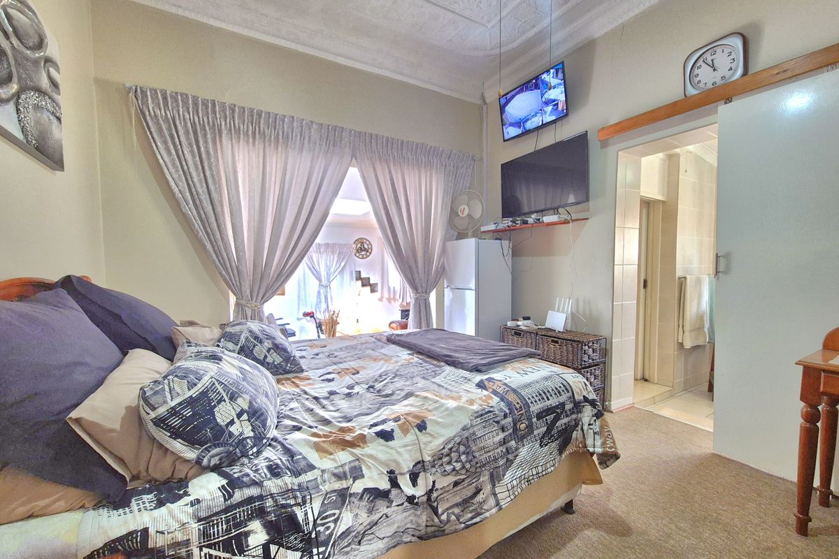 Spacious bedroom featuring ornate ceiling detailing, carpeted flooring, and direct access to an adjoining en-suite bathroom via a sliding door.