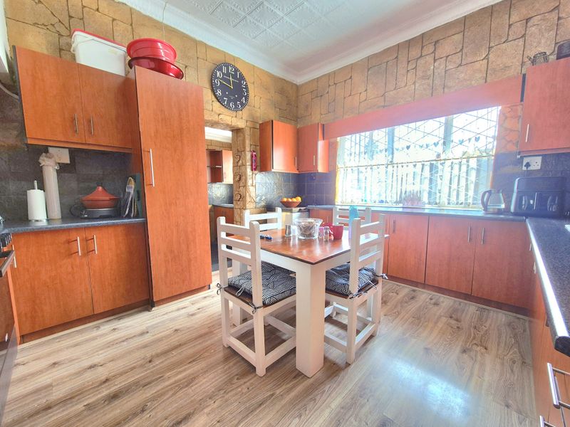 A functional kitchen featuring wood-look cabinetry, laminate countertops, and a distinctive stone-cladding feature wall with ample natural light.