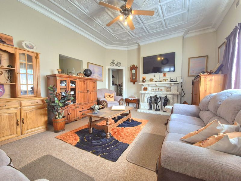 A traditional living room featuring a decorative tin ceiling, crown molding, and a stone-surround fireplace, offering a classic architectural aesthetic.
