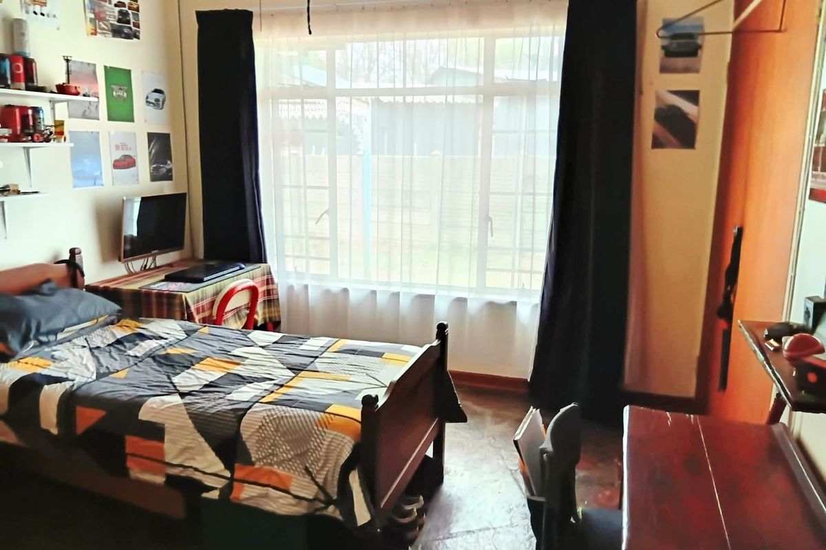 A functional bedroom featuring a large window that provides natural light and built-in shelving for storage.