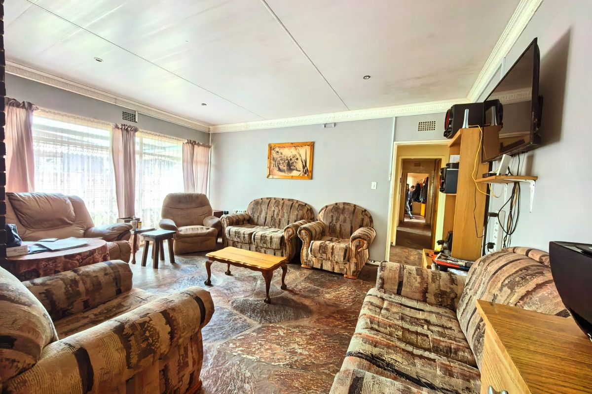 A spacious living room featuring unique stone flooring, recessed lighting, and decorative crown molding, offering a solid foundation for a modern interior update.