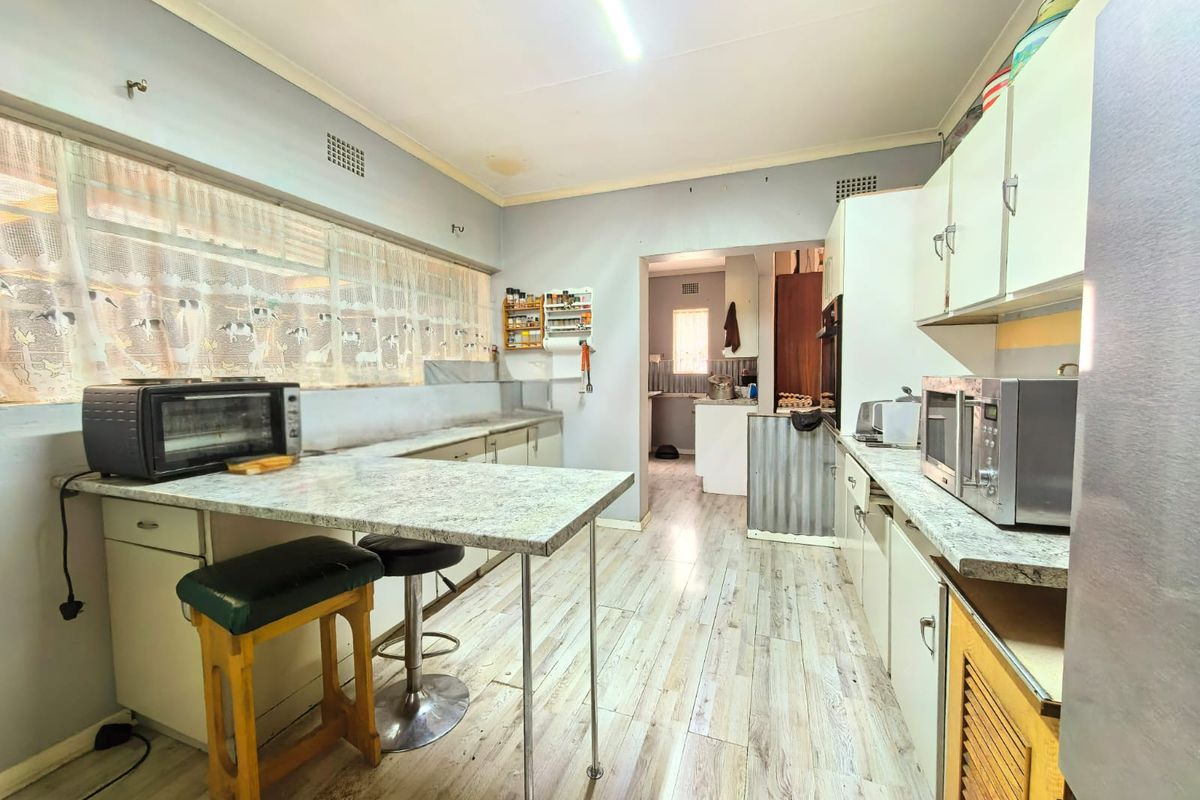 A functional kitchen featuring laminate countertops, built-in cabinetry, and wood-look flooring, offering a practical layout with an adjacent scullery area.