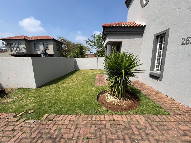 Front exterior view of the property featuring a small lawn, brick paved driveway area, and boundary wall.