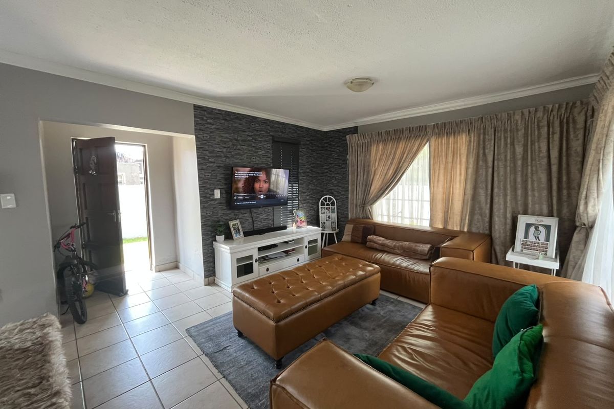 A living room featuring tiled flooring, a textured feature wall, and coved ceiling details, providing a functional and comfortable living space.