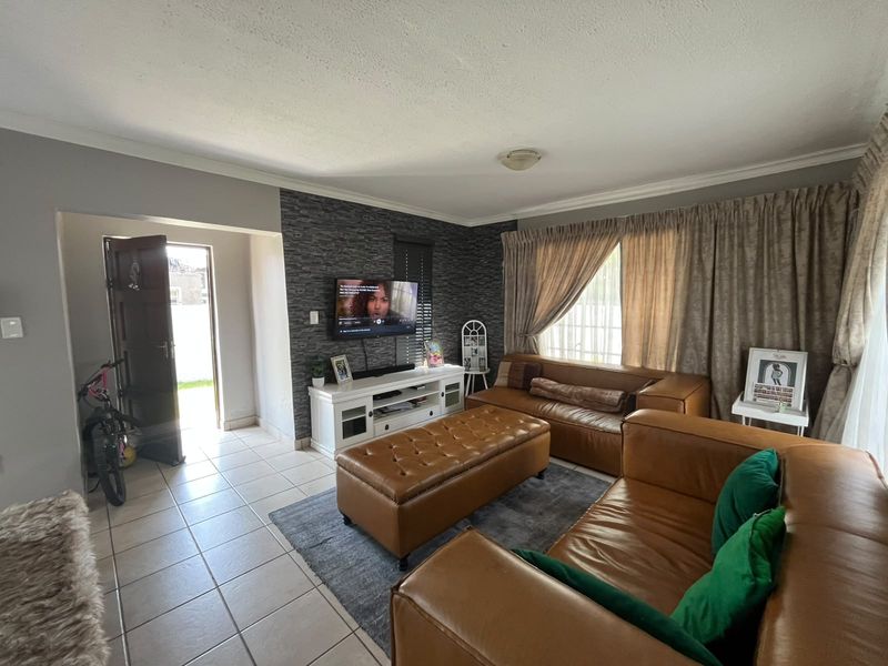 A living room featuring tiled flooring, a textured feature wall, and coved ceiling details, providing a functional and comfortable living space.