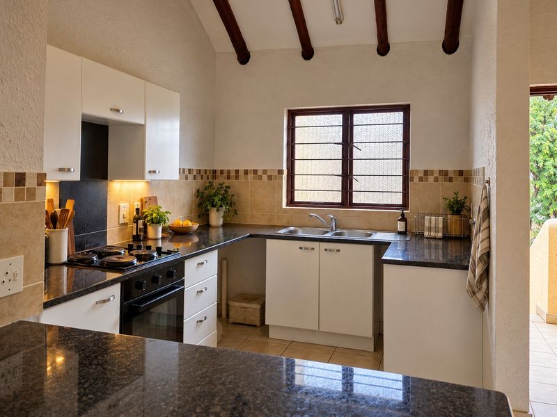 A well-maintained kitchen featuring granite countertops, a built-in oven, gas hob, double sink, and charming exposed timber ceiling beams.