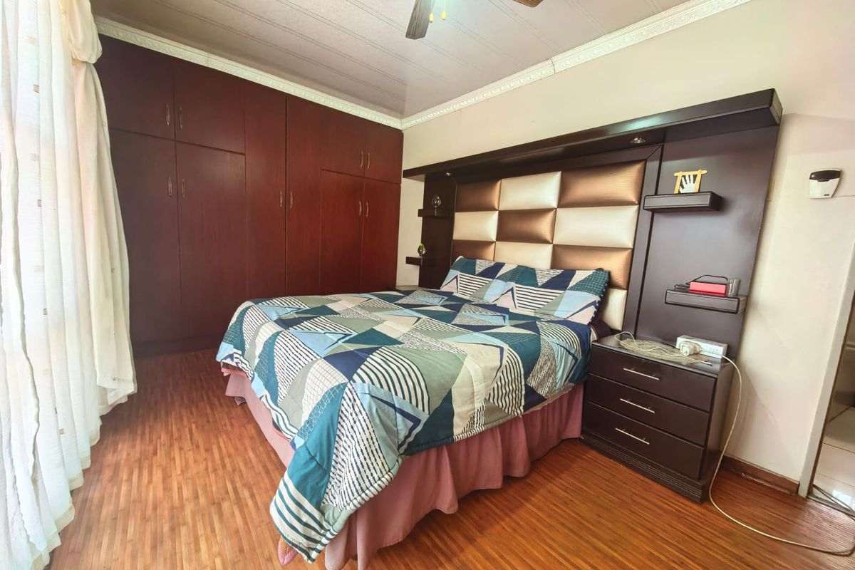 A bedroom featuring laminate flooring, crown molding, a ceiling fan, and extensive built-in cabinetry with an integrated headboard unit.