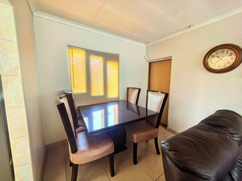 A functional dining area featuring tiled flooring, coved ceilings, and natural light filtered through venetian blinds.