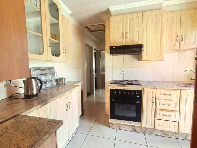 A functional kitchen featuring light wood-finish cabinetry, tiled backsplash, and integrated appliances, offering a classic layout with potential for modern updates.