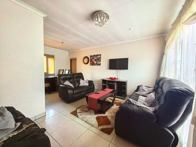 A living room featuring tiled flooring and a coved ceiling, requiring minor cosmetic updates to the ceiling finishes.