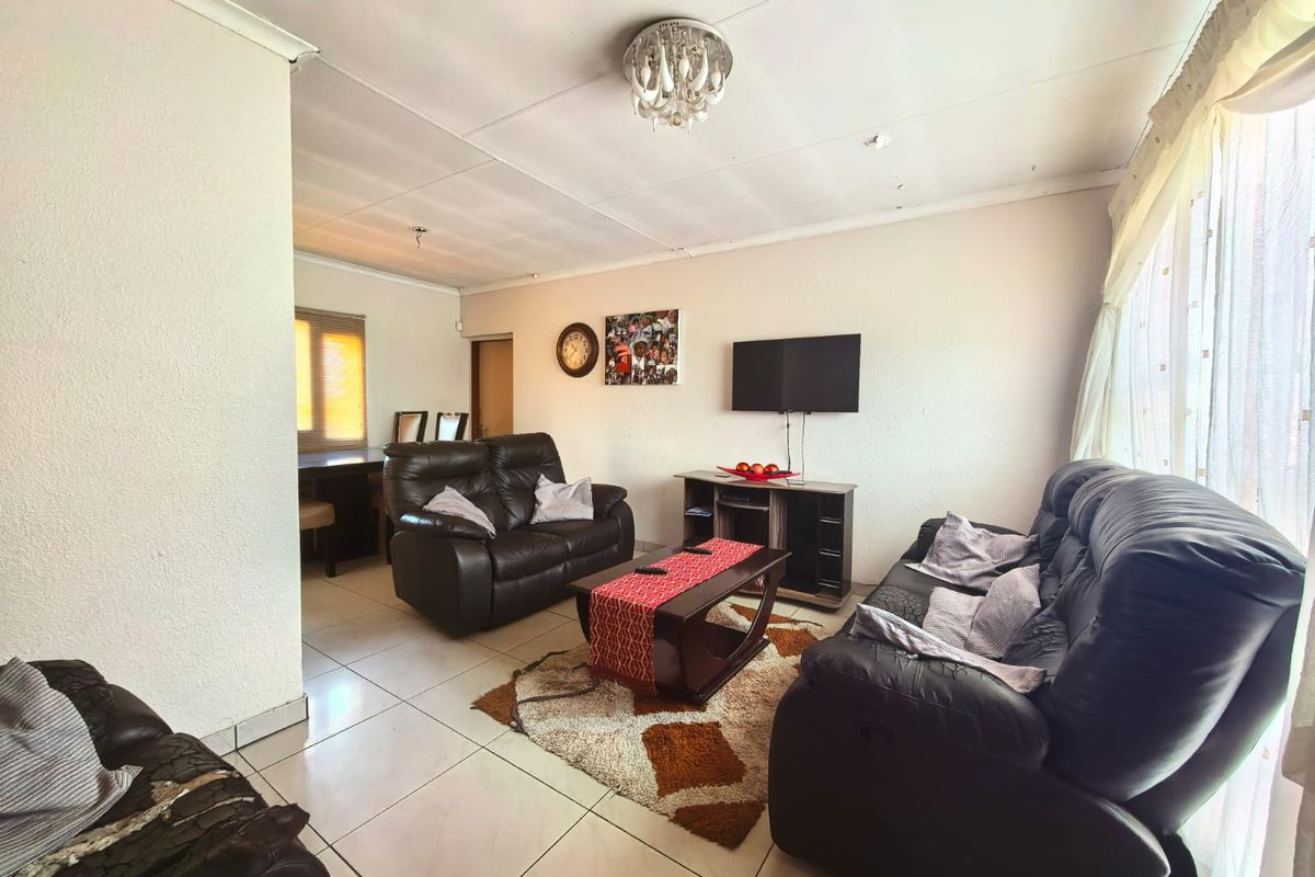 A living room featuring tiled flooring and a coved ceiling, requiring minor cosmetic updates to the ceiling finishes.