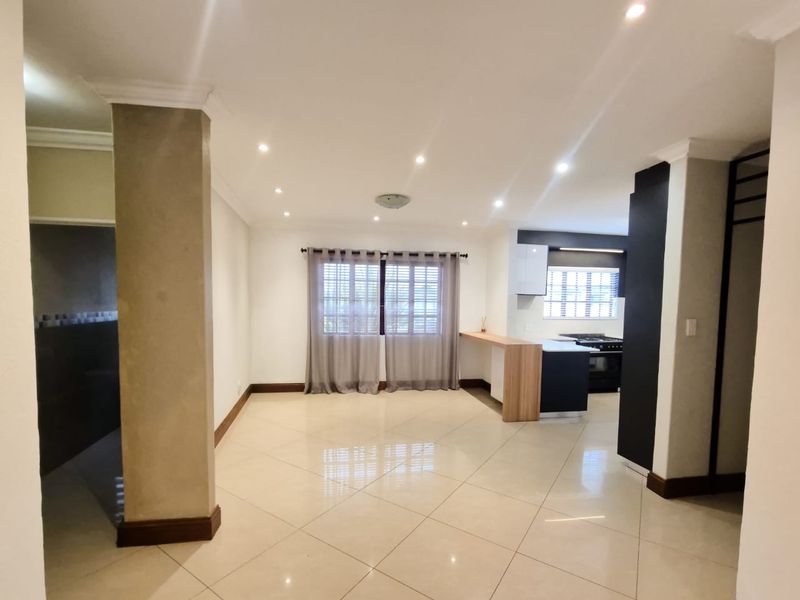 Spacious open-plan living and kitchen area featuring modern porcelain tiling, recessed lighting, and a functional kitchen island with built-in appliances.