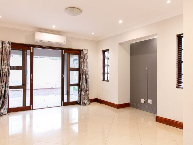 Bright and spacious living area featuring tiled floors, recessed lighting, a split-system air conditioner, and large wooden sliding doors opening to the patio.