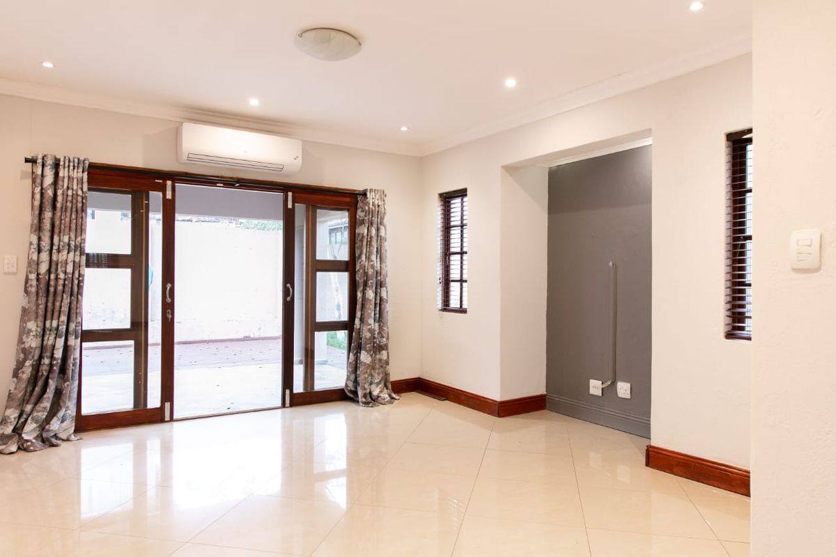 Bright and spacious living area featuring tiled floors, recessed lighting, a split-system air conditioner, and large wooden sliding doors opening to the patio.