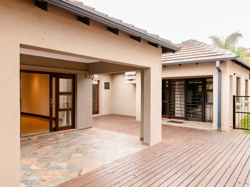A spacious covered patio area featuring a combination of tiled flooring and timber decking, providing seamless access to the interior through sliding glass doors.
