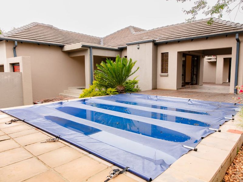 Outdoor pool area featuring a covered swimming pool, tiled decking, and direct access to the home's covered patio and main structure.