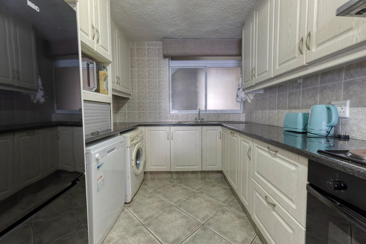 A functional kitchen featuring light-toned built-in cabinetry, granite countertops, tiled backsplash, and integrated appliances including an oven and hob.