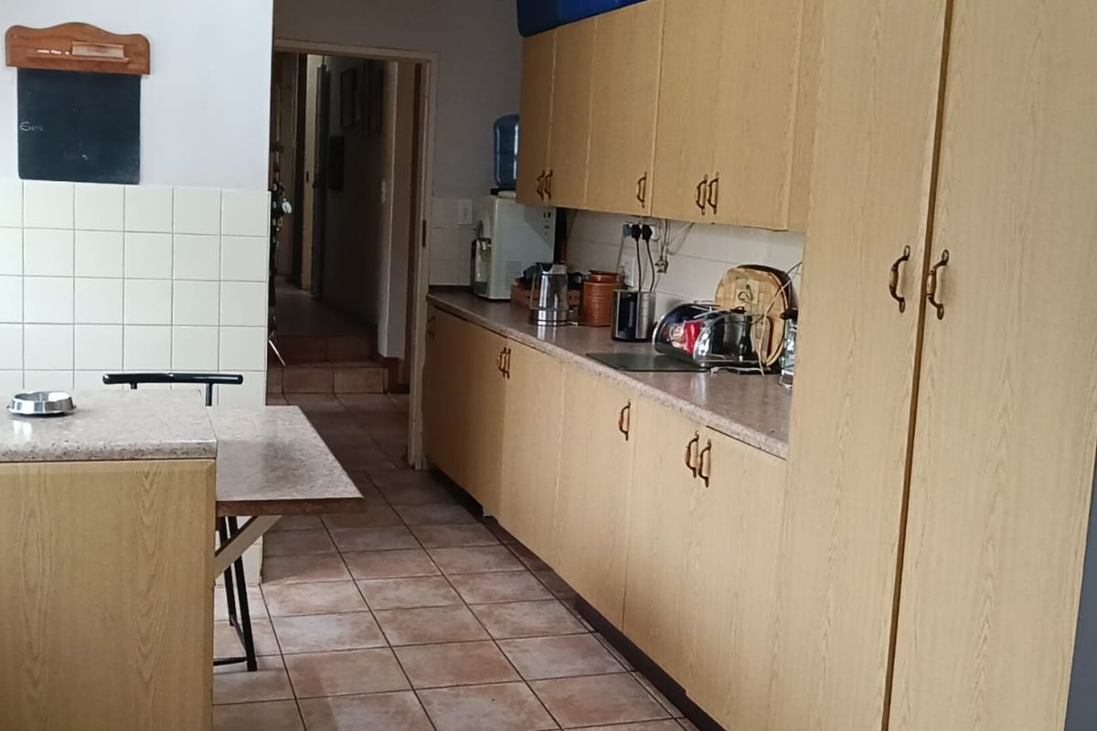 A functional kitchen featuring laminate cabinetry, tiled backsplash, and tiled flooring, offering a practical layout with ample storage space.