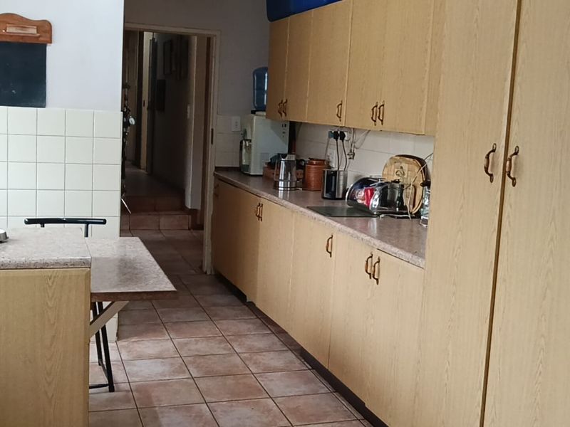 A functional kitchen featuring laminate cabinetry, tiled backsplash, and tiled flooring, offering a practical layout with ample storage space.