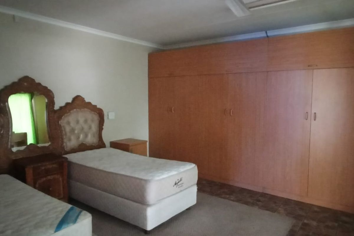 A bedroom featuring extensive wall-to-wall built-in wooden cupboards and a ceiling fan, offering ample storage space.