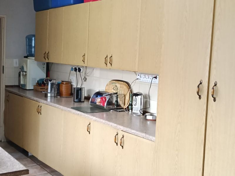 A functional kitchen featuring light wood-tone laminate cabinetry, ample counter space, and tiled flooring, offering a practical layout for daily use.