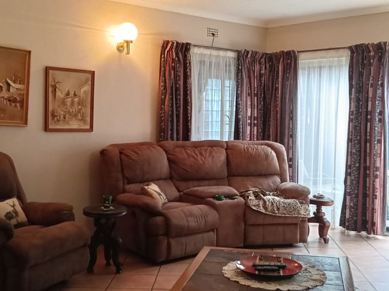 A comfortable living room featuring tiled flooring and a large sliding glass door providing access to an outdoor patio area.