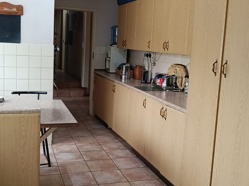 A functional kitchen featuring laminate cabinetry, tiled flooring, and a tiled backsplash, offering a dated aesthetic ready for modernization.