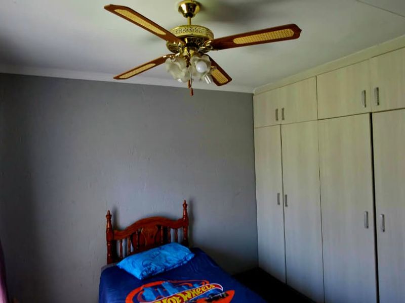 A bedroom featuring built-in cupboards and a ceiling fan, providing functional storage and climate control.