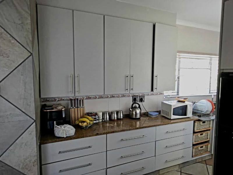 A functional kitchen featuring granite countertops, ample built-in cabinetry, and a tiled backsplash, providing a practical workspace with modern finishes.
