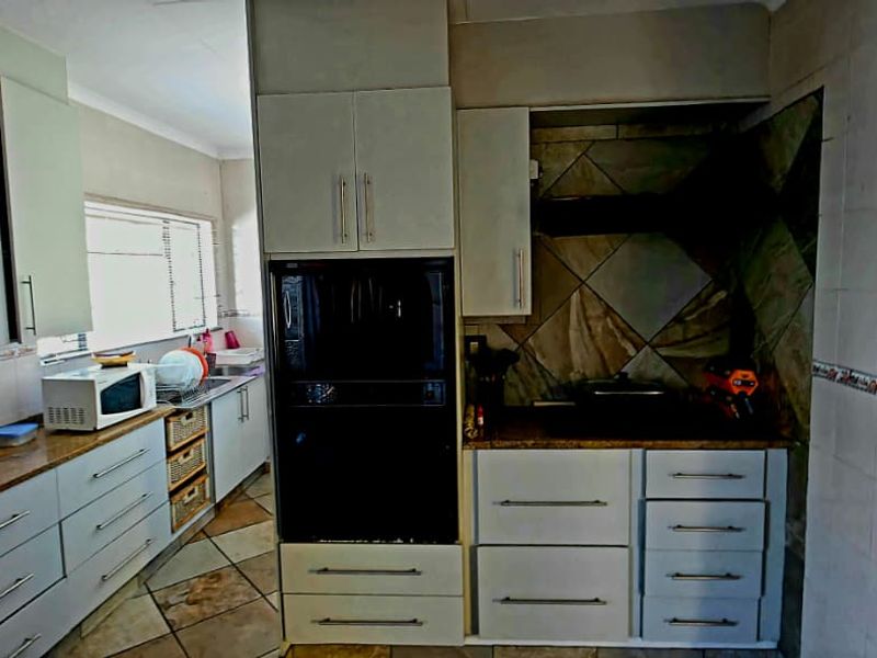 A functional kitchen featuring built-in cabinetry, integrated oven, extractor fan, and tiled splashbacks with ample counter space.