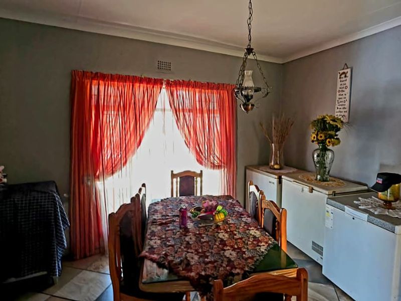 A functional dining area featuring tiled flooring, cove cornicing, and a central pendant light fixture, providing a practical space for family meals.