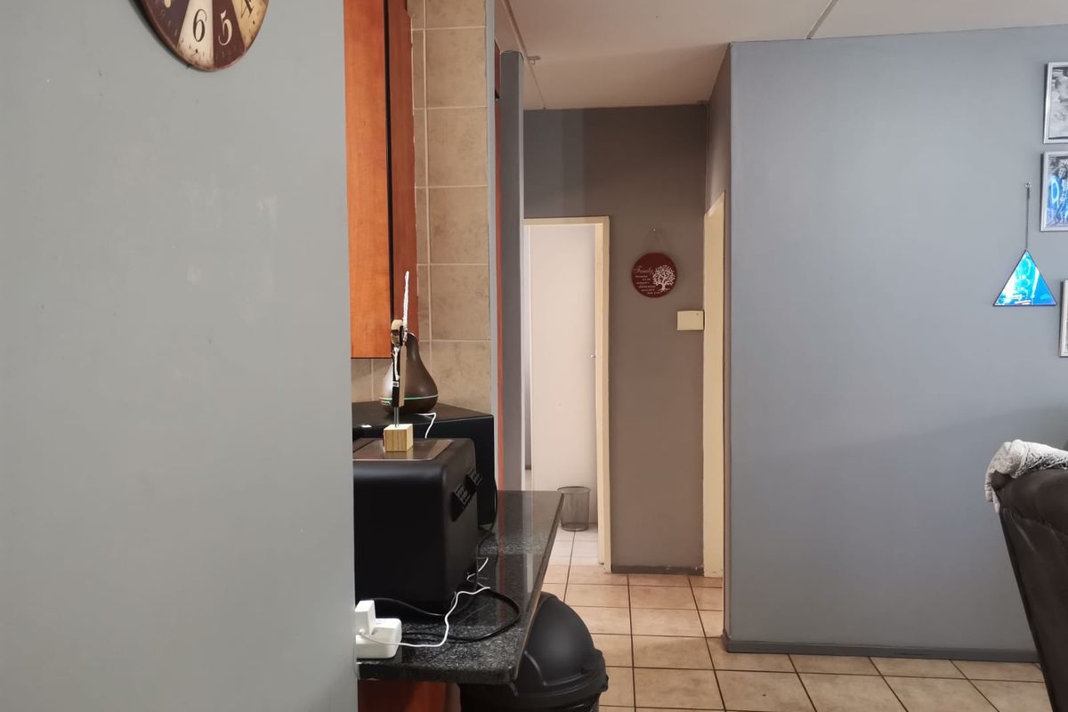 A view of a kitchen area featuring granite countertops and tiled flooring, leading into a hallway.