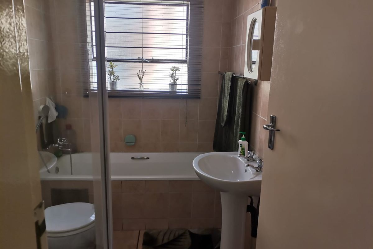 A functional bathroom featuring a pedestal basin, bathtub, and a separate shower enclosure with tiled finishes throughout.