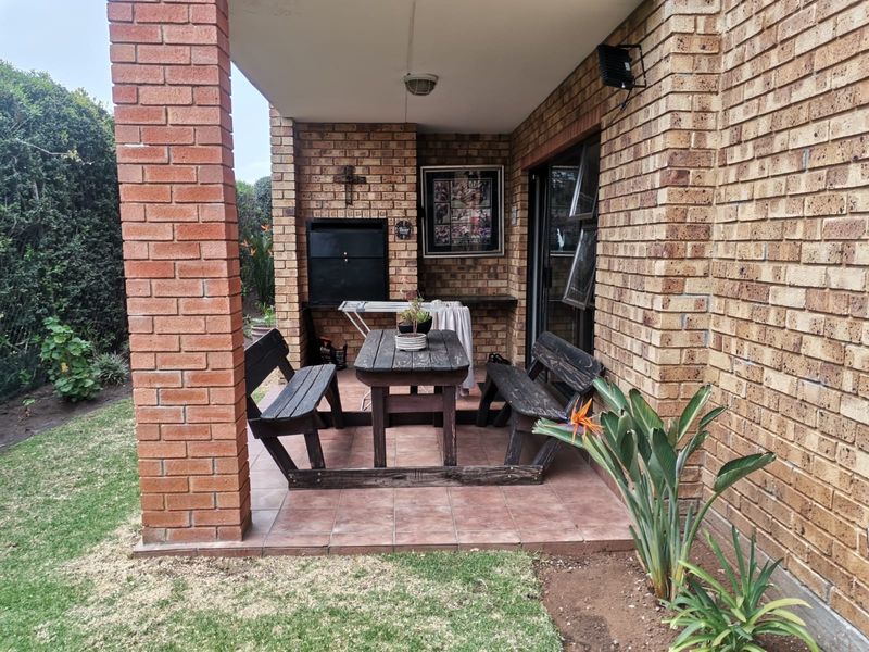 A covered patio area featuring a built-in braai, brick construction, and tiled flooring, providing a functional outdoor entertainment space.