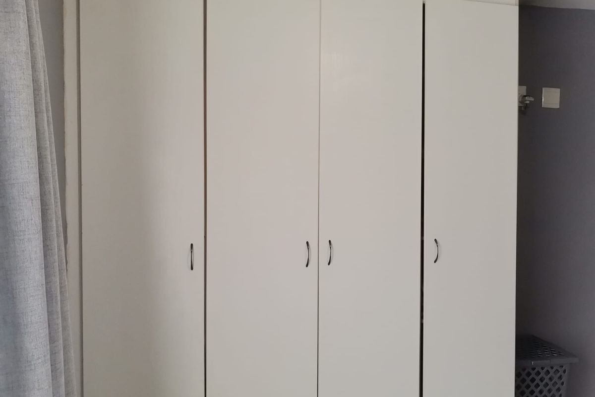 A bedroom featuring a white built-in wardrobe with simple handles.
