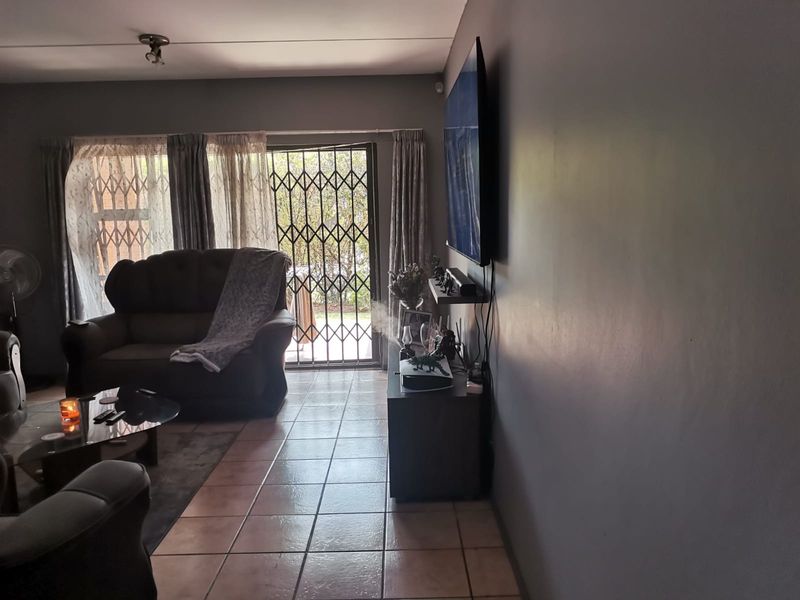 A living room featuring tiled flooring and a sliding door with a security gate, providing access to the outdoor area.
