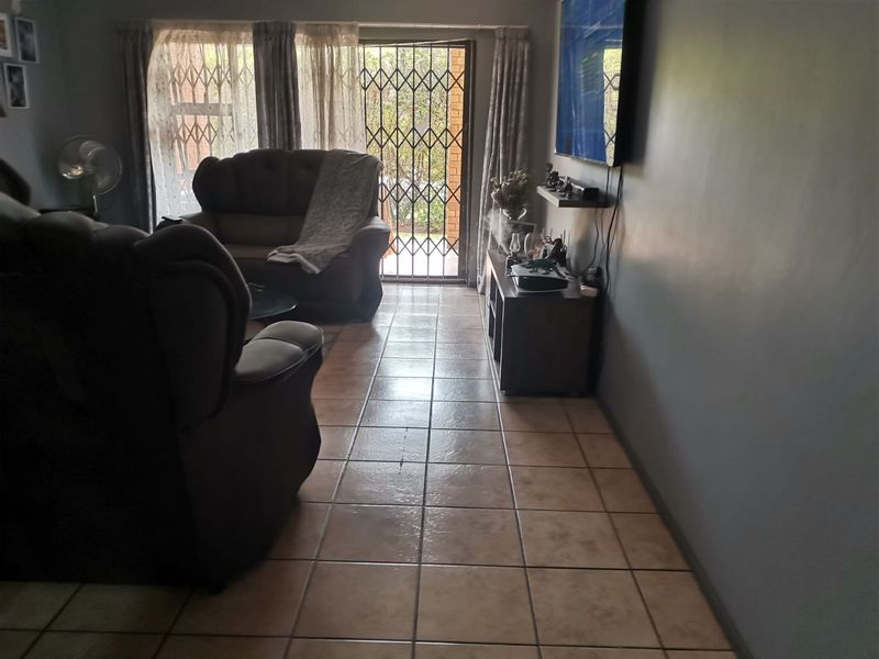 A living room featuring tiled flooring and a sliding glass door with a security gate leading to the exterior.