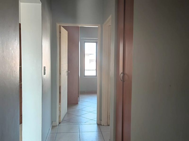 A functional hallway featuring tiled flooring, a built-in cupboard, and access to adjacent rooms within the apartment.