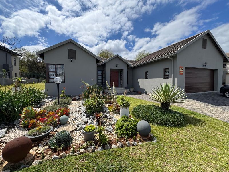 A well-maintained single-story house featuring a paved driveway, double garage, and landscaped front garden with a secure entrance.