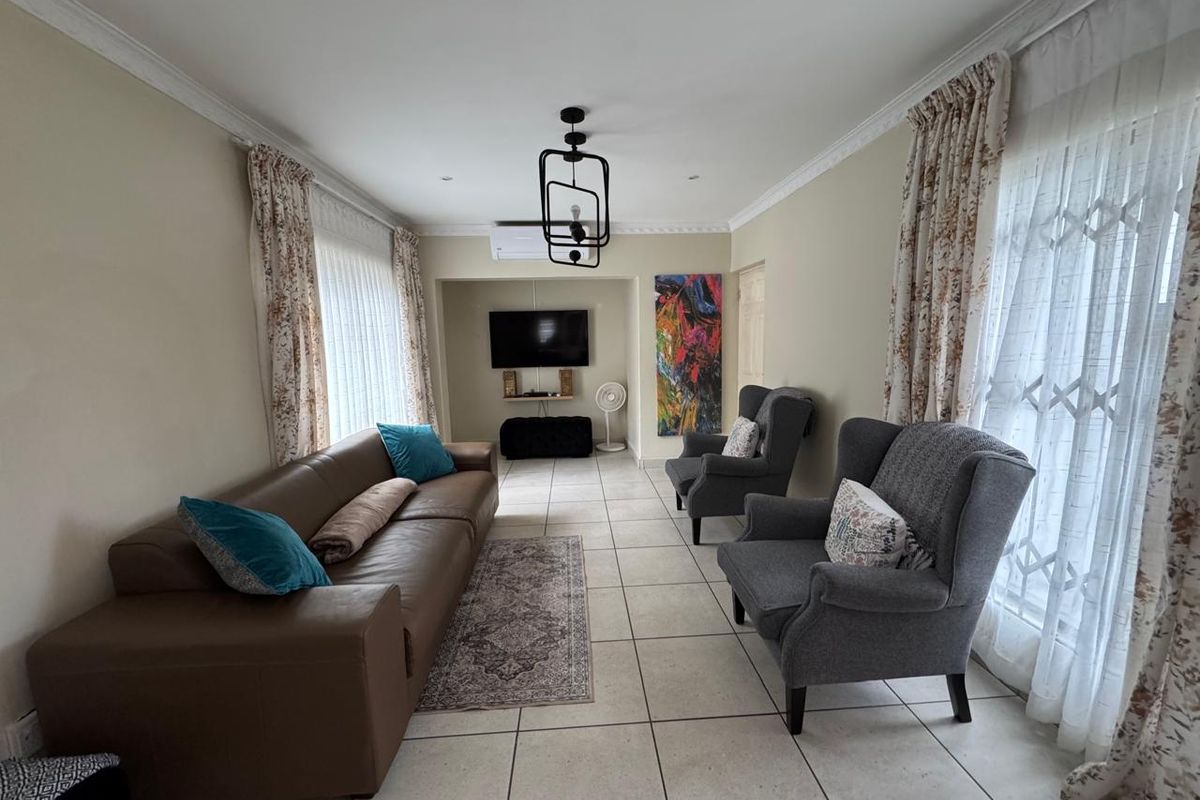 A well-maintained living room featuring tiled flooring, crown molding, and a split-system air conditioner, offering a comfortable and functional space.