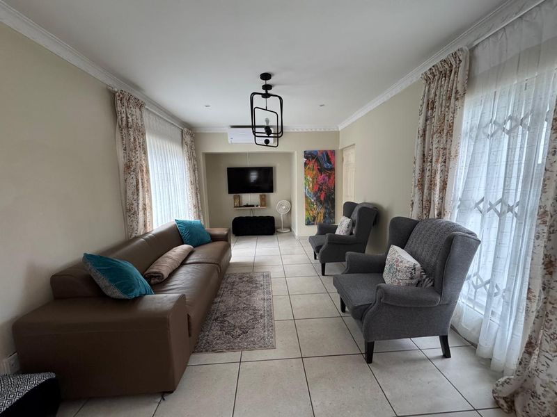 A well-maintained living room featuring tiled flooring, crown molding, and a split-system air conditioner, offering a comfortable and functional space.