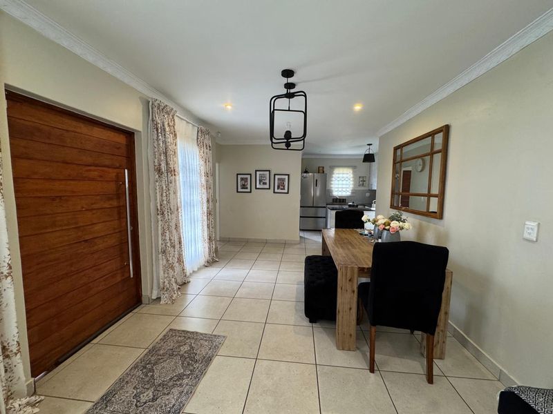 Open plan living and dining area featuring tiled flooring, crown molding, and a prominent solid wood entrance door.