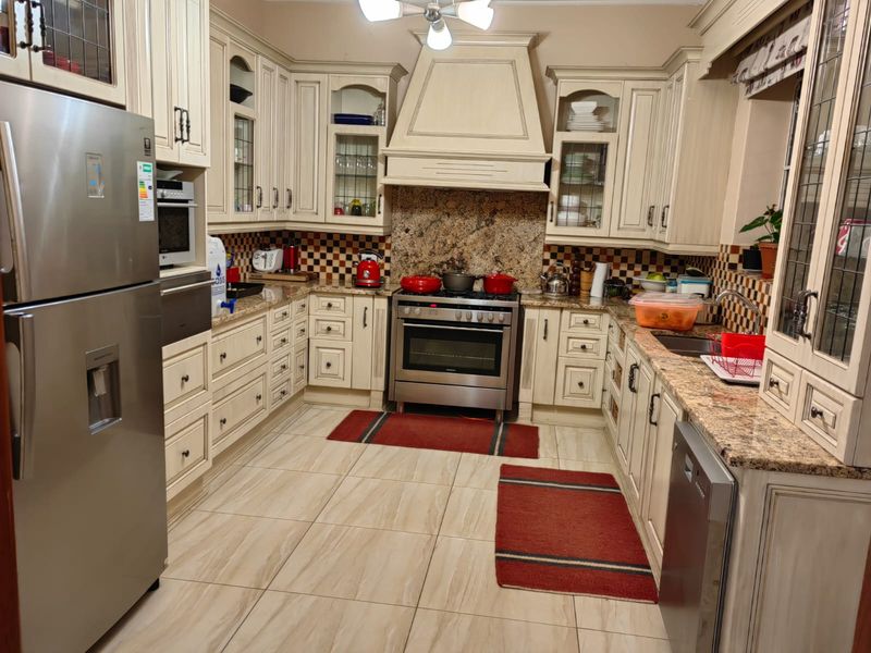 A well-appointed kitchen featuring granite countertops, extensive built-in cabinetry, a gas stove with an extractor hood, and tiled flooring.