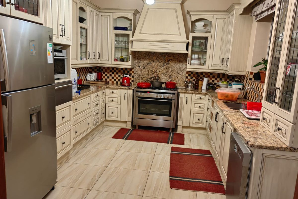 A well-appointed kitchen featuring granite countertops, extensive built-in cabinetry, a gas stove with an extractor hood, and tiled flooring.