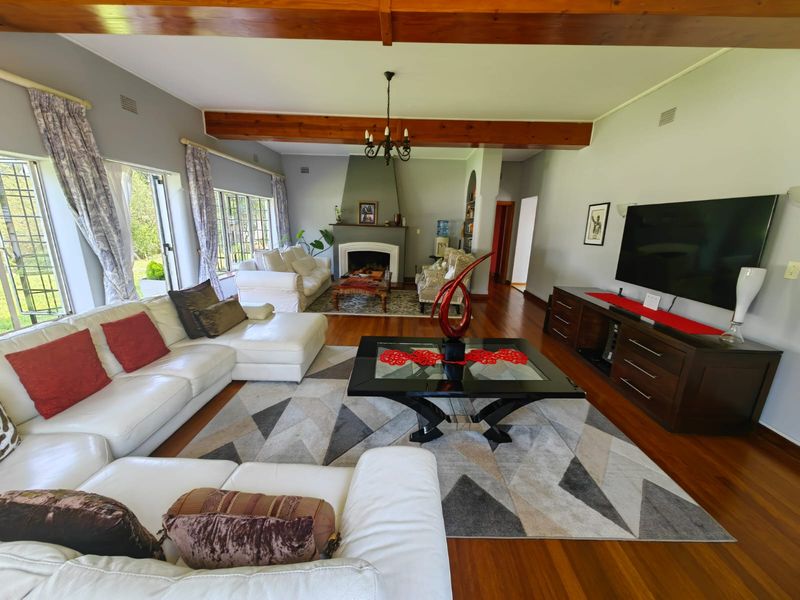 Spacious living room featuring exposed timber ceiling beams, hardwood flooring, and a central fireplace, creating a warm and inviting atmosphere.