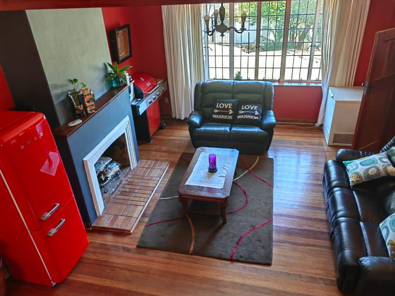 A living room featuring timber flooring, a fireplace with a mantel, and large windows with security bars, providing a functional and cozy living space.