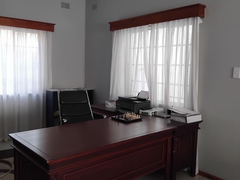 A functional home office featuring tiled flooring, neutral wall finishes, and timber window pelmets, providing a clean and professional workspace.